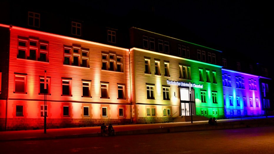 Gebäude der Technischen Universität Clausthal nachts in Regenbogenfarben beleuchtet